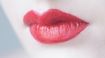 Close-up of a woman's lips, with bright red lipstick and white skin